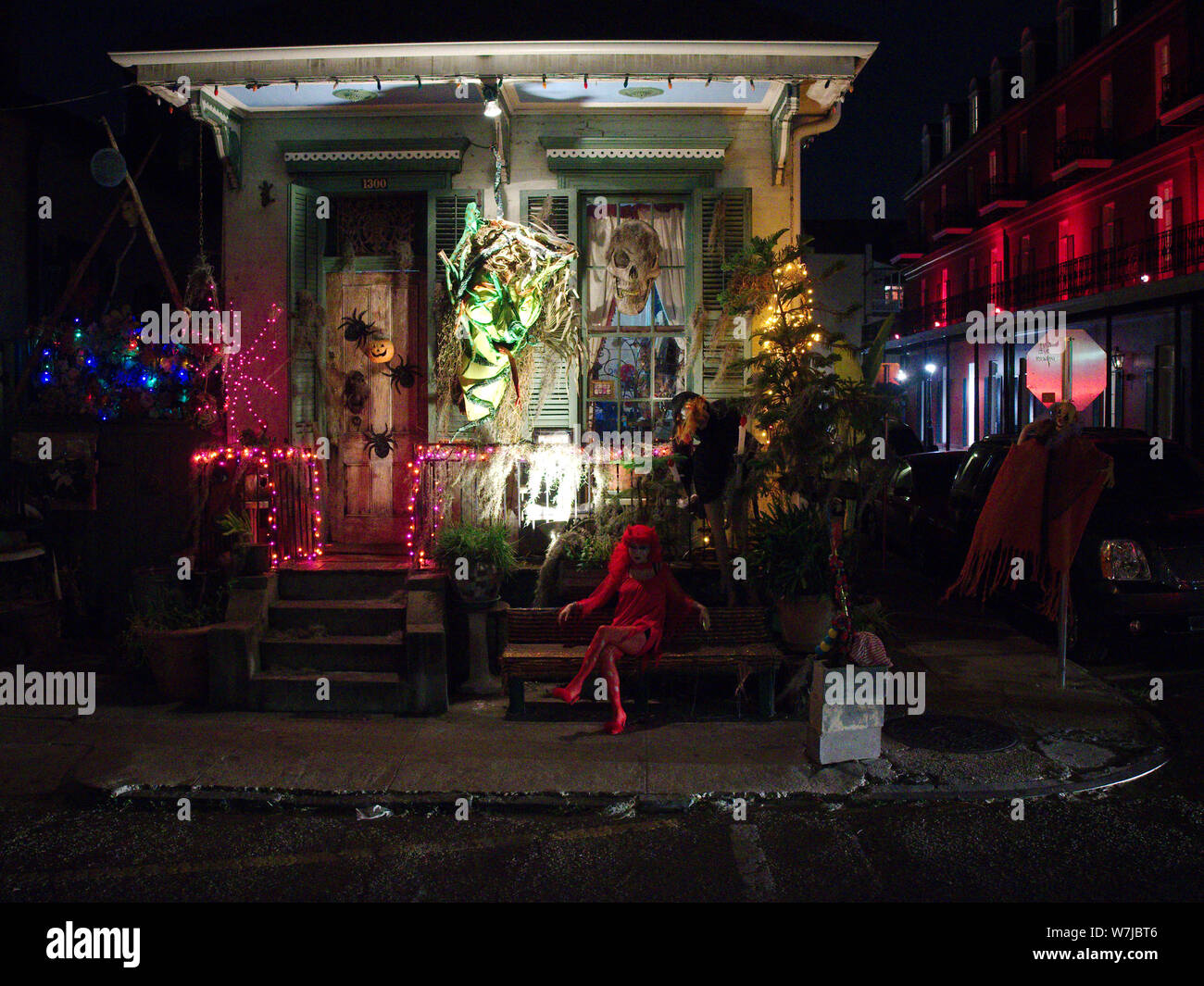 New Orleans, Louisiana, USA - October 31, 2018: A woman wearing a costume sits in front of a decorated house on Halloween night. Stock Photo