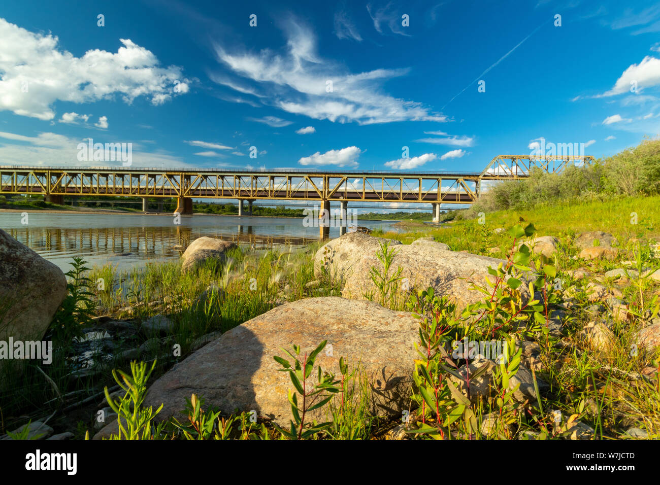 Beautiful calm clear afternoon view of the distant train bridge over the South Saskatchewan River Stock Photo