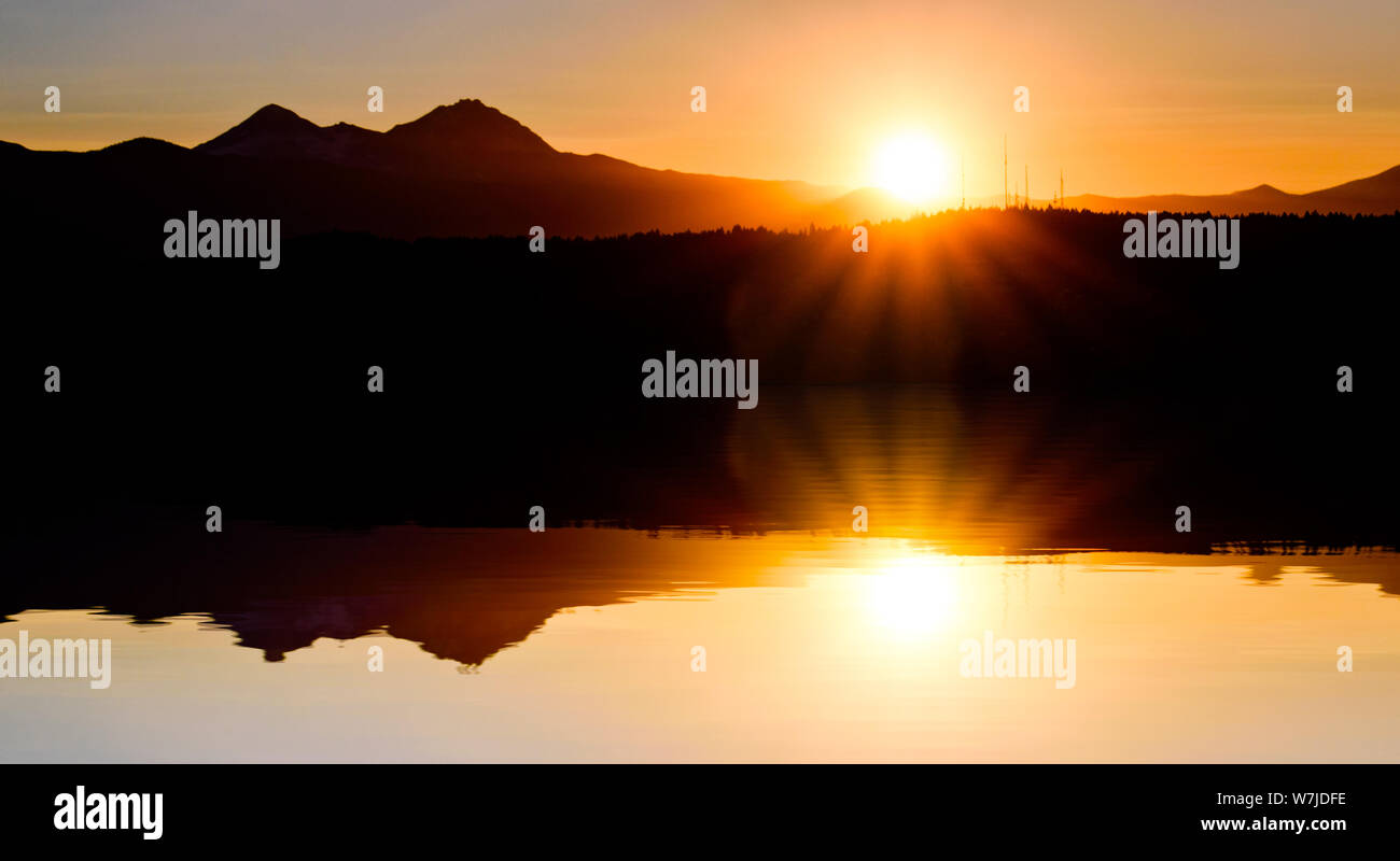 Beautiful Glassy Body of Water Reflecting a Warm Glowing Sunset over the Oregon Cascades Stock Photo
