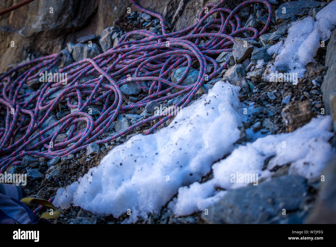 Ropes, used by rock climbers, lie at the base of a cliff in the snow in a mountain valley in New Zealand Stock Photo