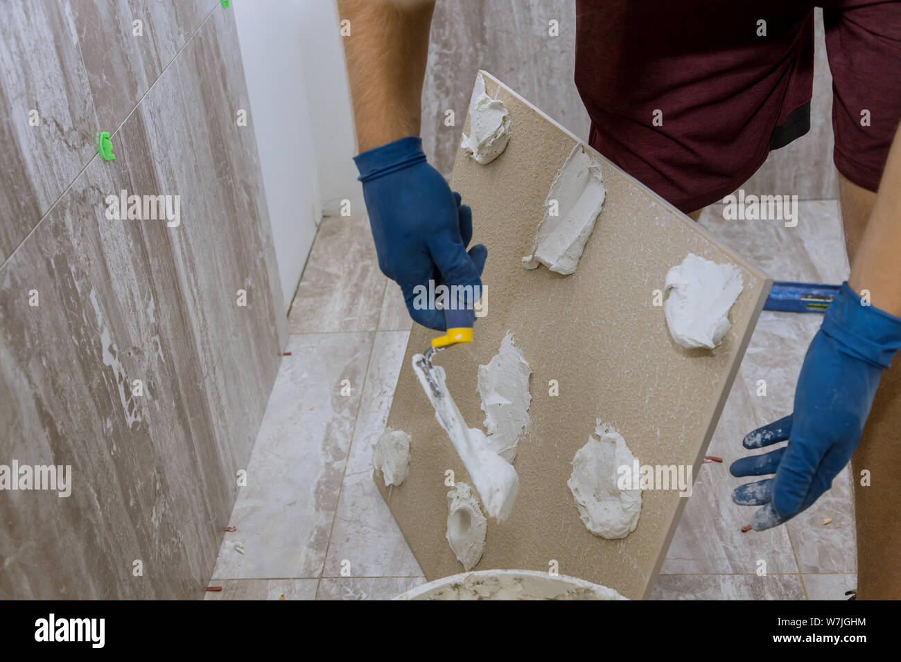 Spreading wet mortar before applying tiles on bathroom floor tile Stock