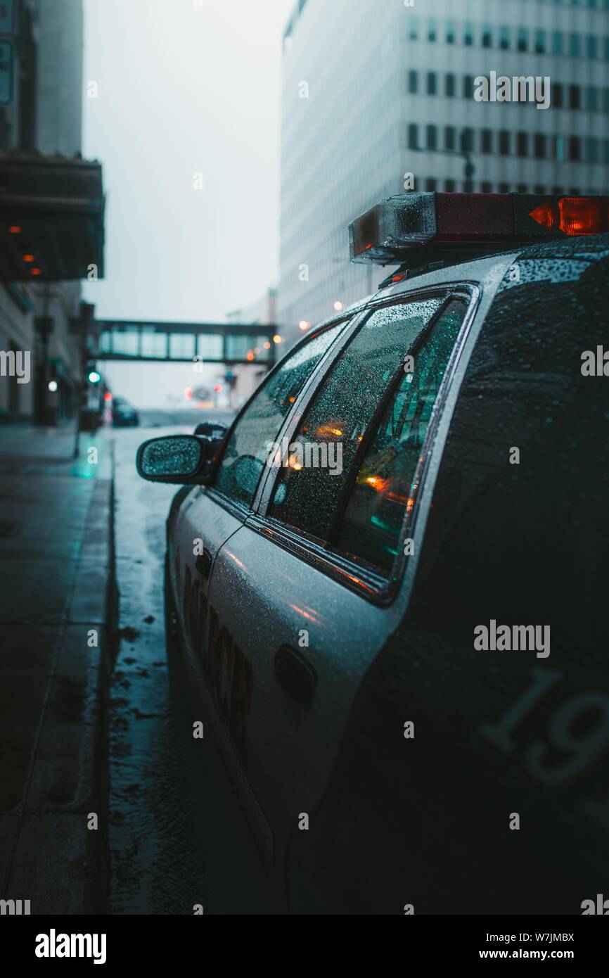 Vertical closeup shot of a polica car parked on a rainy road Stock Photo