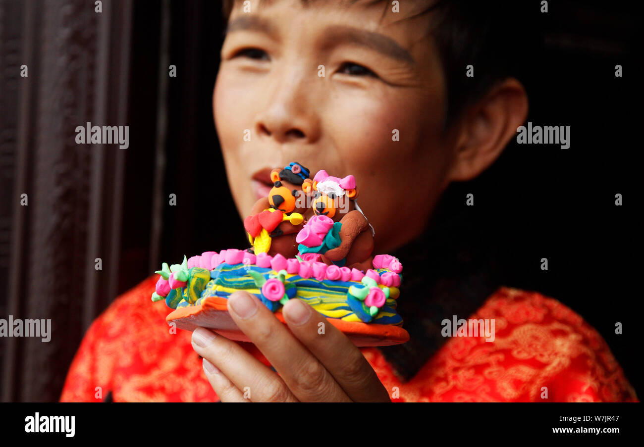 42-year-old Chinese bridegroom Li Haimin dressed in traditional costumes, who is 4 foot 8 inches tall, shows clay figures of bears made by himself to Stock Photo