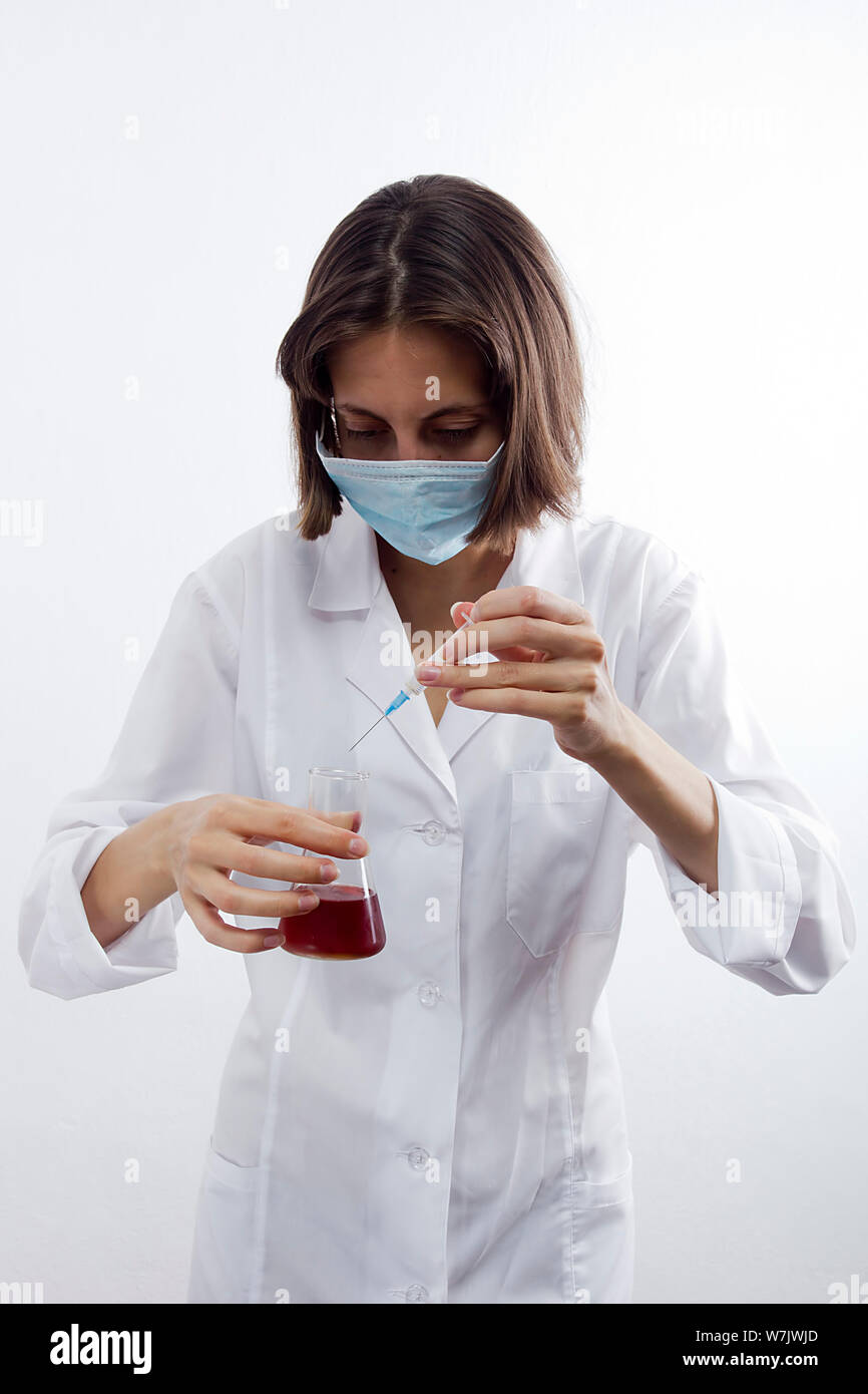 Young female laboratory technician in mask on white background Stock Photo