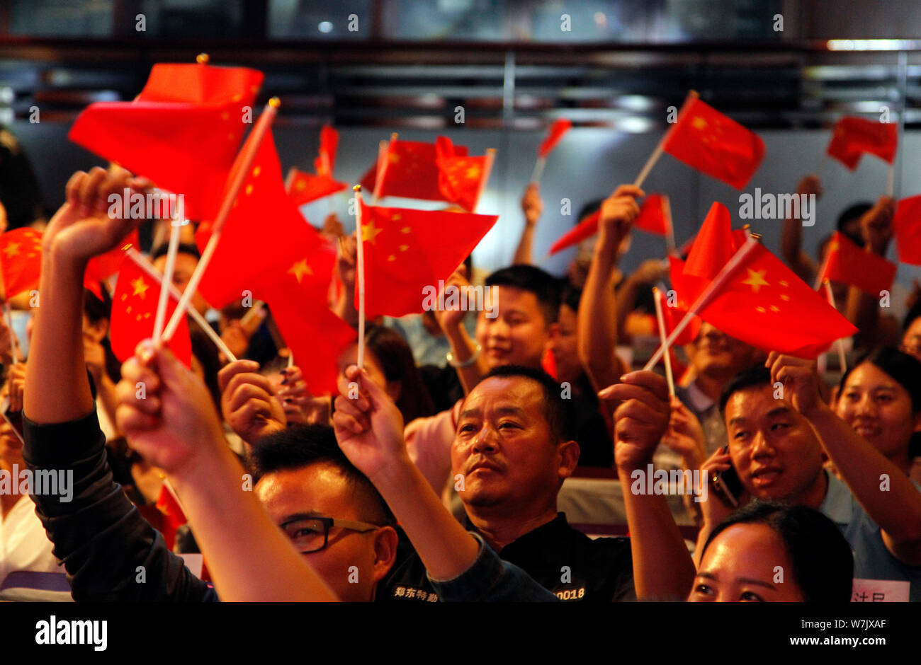 Local residents hold red flags during a celebration event ahead of the National Day in Zhengzhou city, central China's Henan province, 26 September 20 Stock Photo