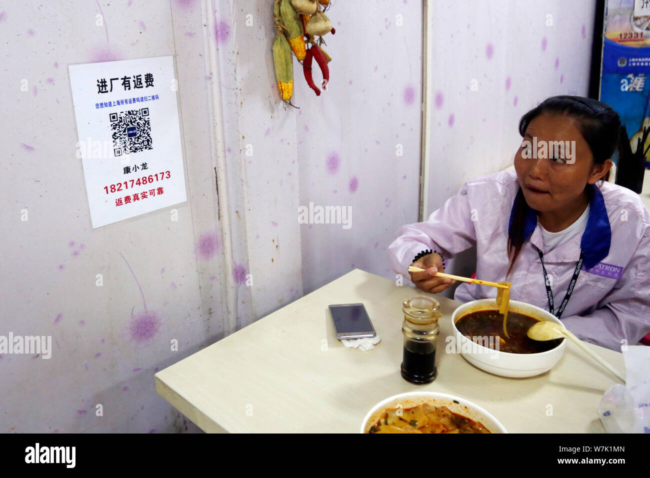 A Chinese worker eats meal at a roadside restaurant after leaving work outside the Pegatron Changshuo factory for the assembly of Apple's iPhone and o Stock Photo