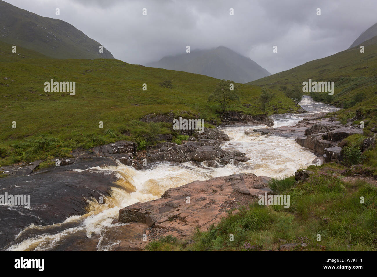 The  River Etive flows through Glen Etive in the Scottish highlands near Glencoe on a moody rainy day with low cloud Stock Photo