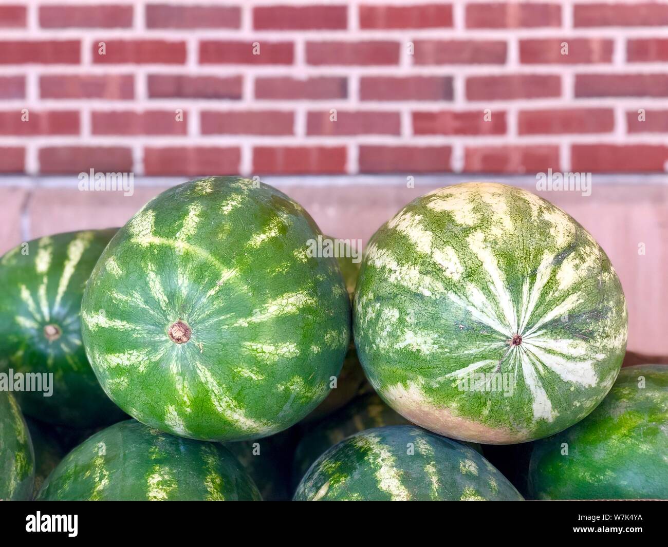 Whole watermelons pile fresh summer fruit bricks wall background Stock Photo