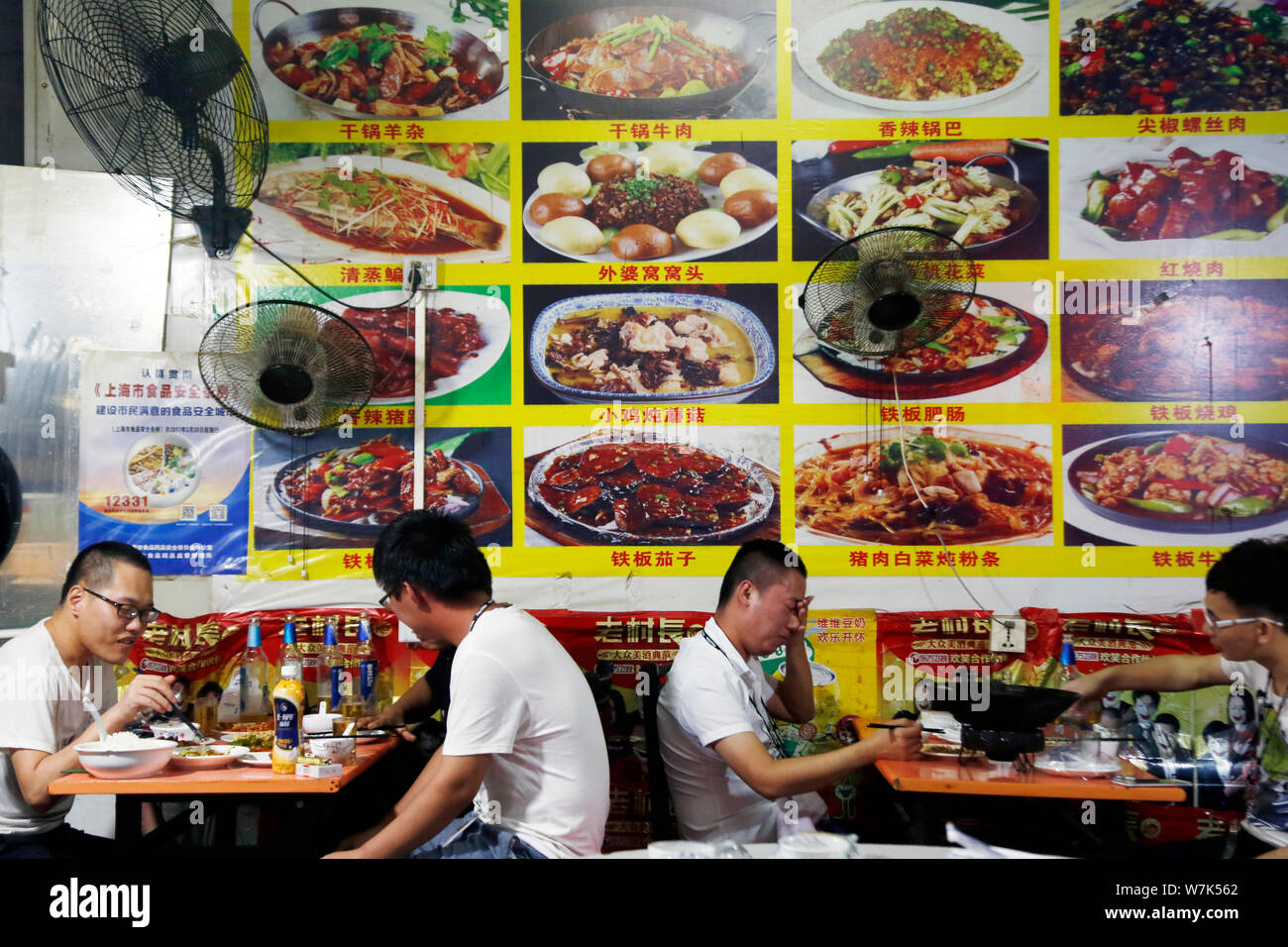 Chinese workers eat meals at a roadside restaurant after leaving work outside the Pegatron Changshuo factory for the assembly of Apple's iPhone and ot Stock Photo