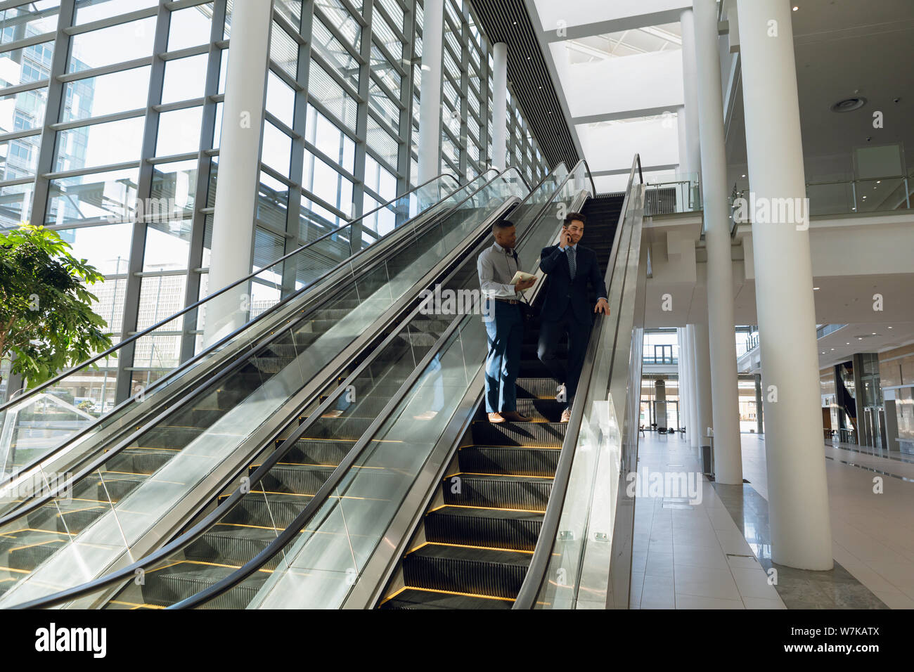 Young businessmen standing on escalator Stock Photo