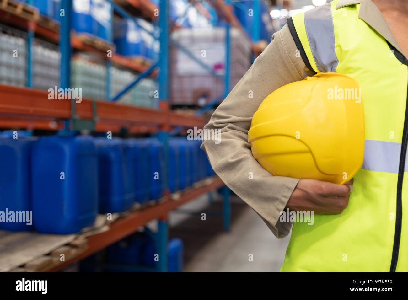 Female worker holding hard hat in warhouse Stock Photo