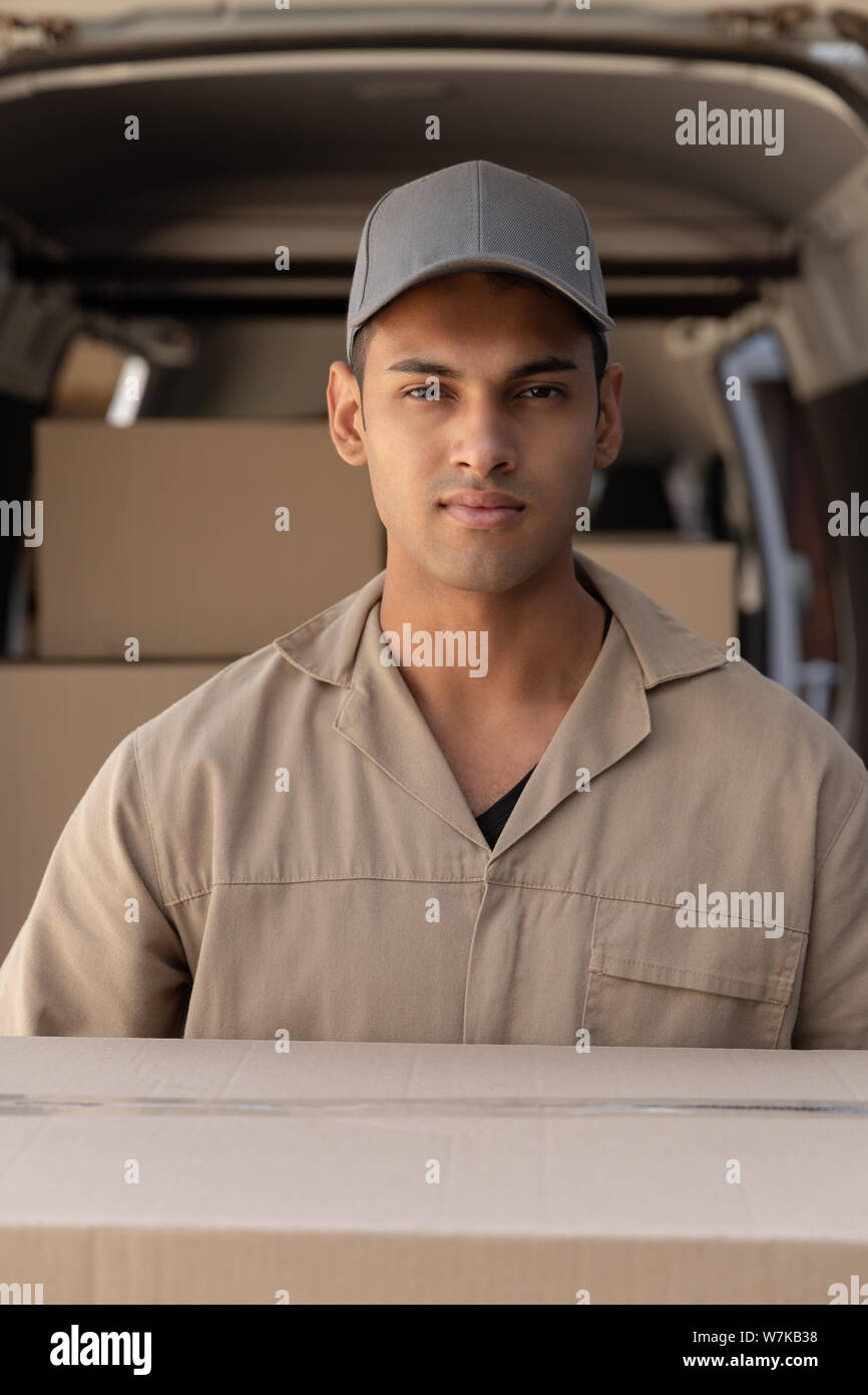 Delivery man carrying cardboard boxes outside the warehouse Stock Photo