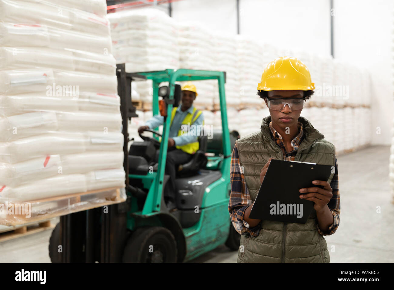 Female worker writing on clipboard in warehouse Stock Photo - Alamy