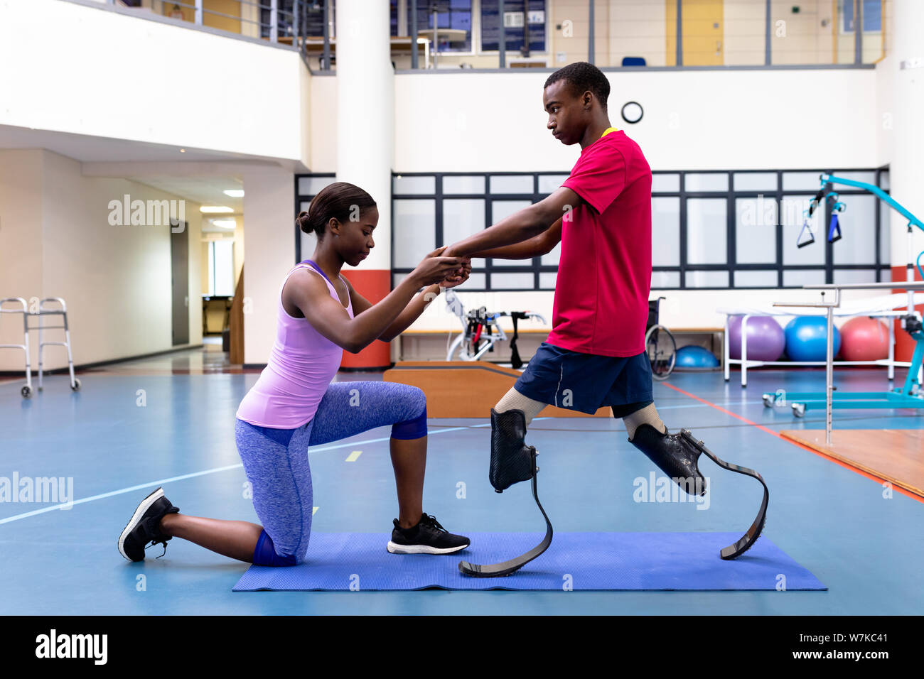 Female physiotherapist helping disabled man walk with prosthetic