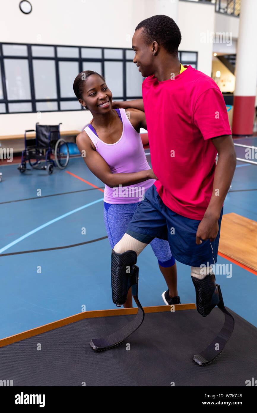 Physiotherapist helping disabled man walk with prosthetic leg on ramp ...