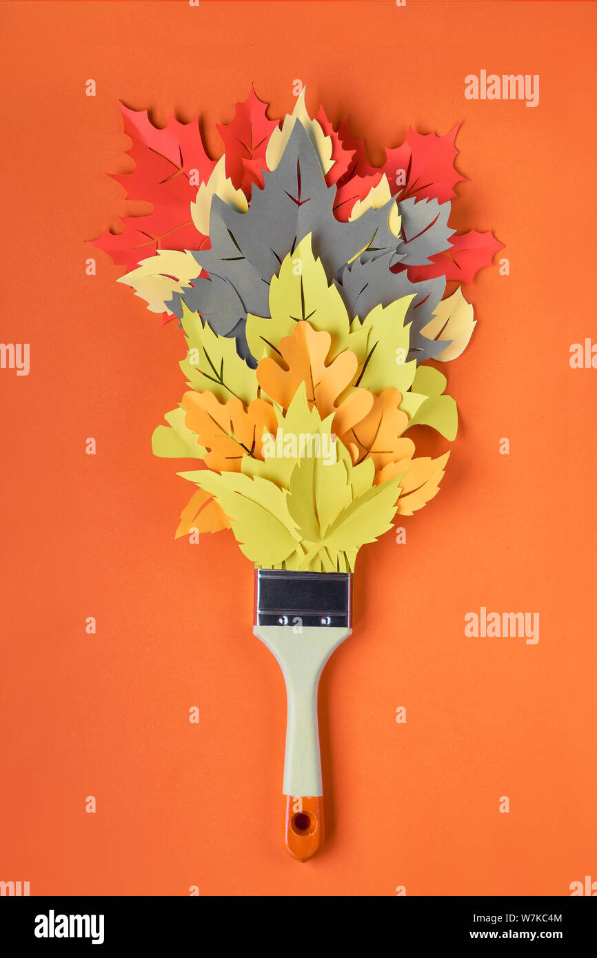 Top view on flat lay with brush loaded with paint made from paper Autumn leaves on orange paper background. Concept home renovation background in red, Stock Photo