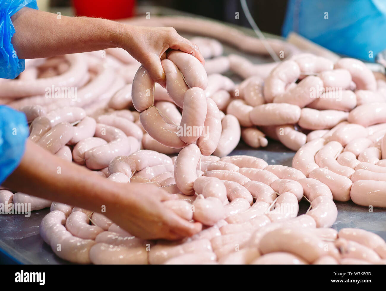 Butchers processing sausages at the meat factory. Stock Photo