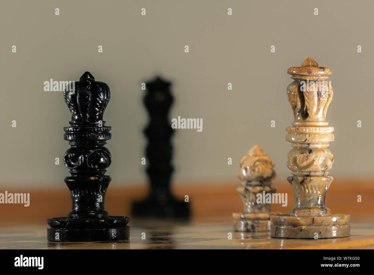 Chess board with handmade stone pieces. Queen, King, Pawn, and distant King. Stock Photo