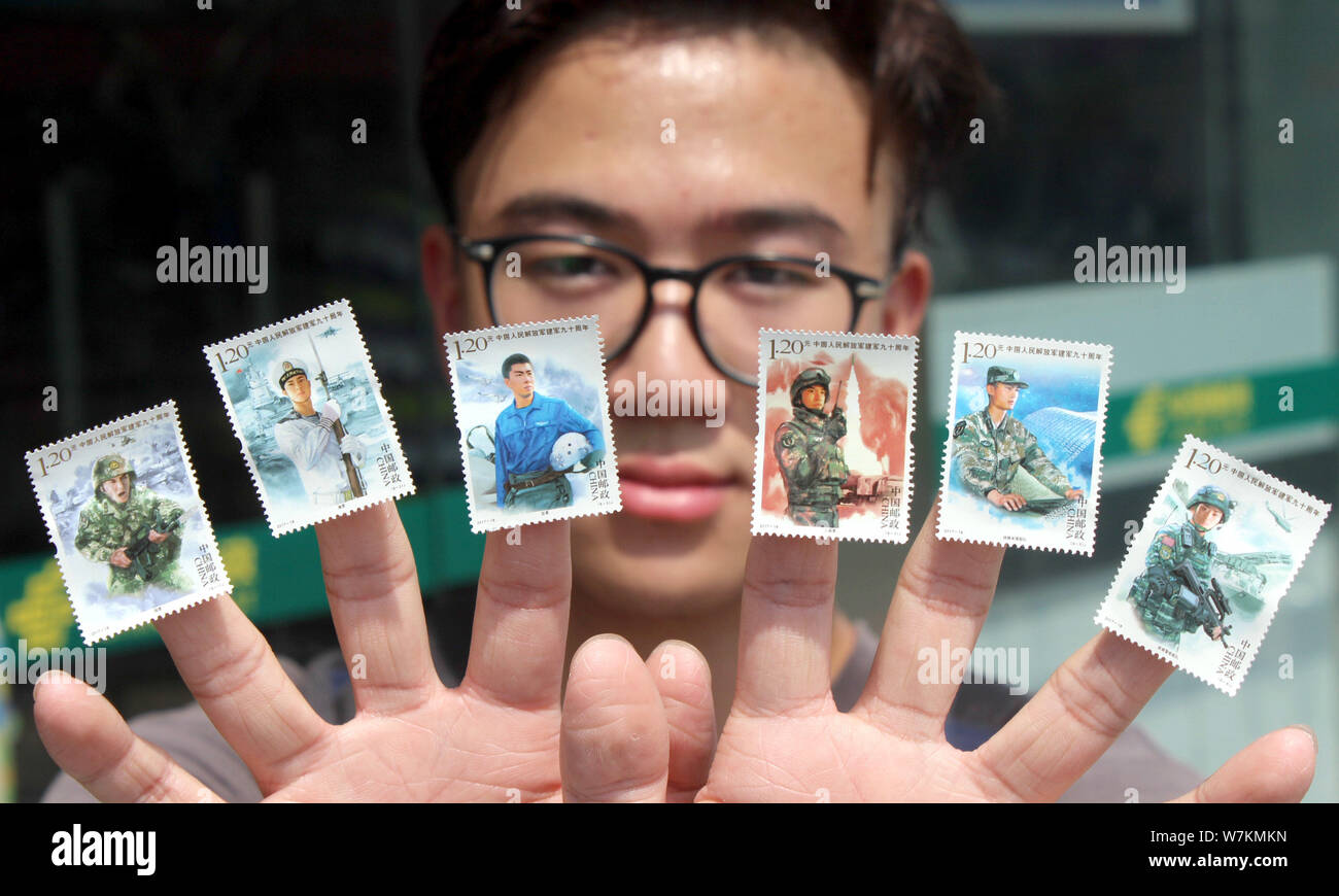 A stamp collecting enthusiast shows commemorative stamps for the 90th anniversary of the founding of the Chinese People's Liberation Army (PLA) at a b Stock Photo