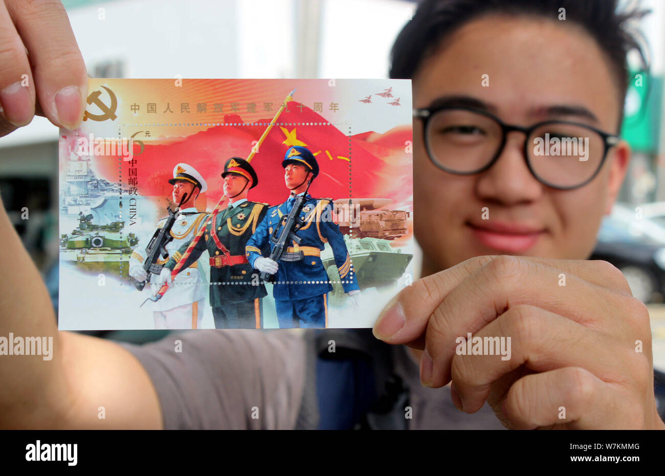 A stamp collecting enthusiast shows the souvenir sheet for the 90th anniversary of the founding of the Chinese People's Liberation Army (PLA) at a bra Stock Photo