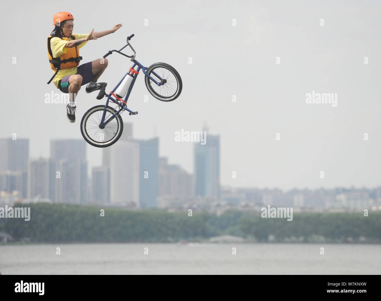 A BMX (Bicycle Motocross) rider jumps into the East Lake to cool off amid hot weather from a plank road during the 'Lake-jumping' festival in Wuhan ci Stock Photo
