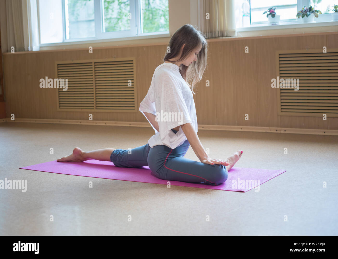 Young slim woman with blonde hair sitting on the yoga mat and doing ...