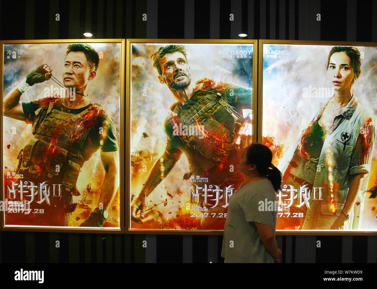 A Chinese Filmgoer Walks Past Posters Of The Chinese Action Movie Wolf