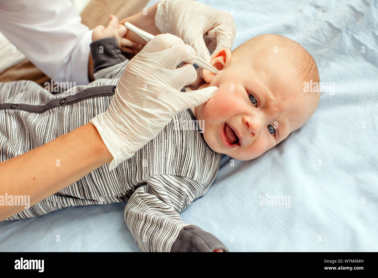 Nurse cleaning ear of newborn baby Stock Photo