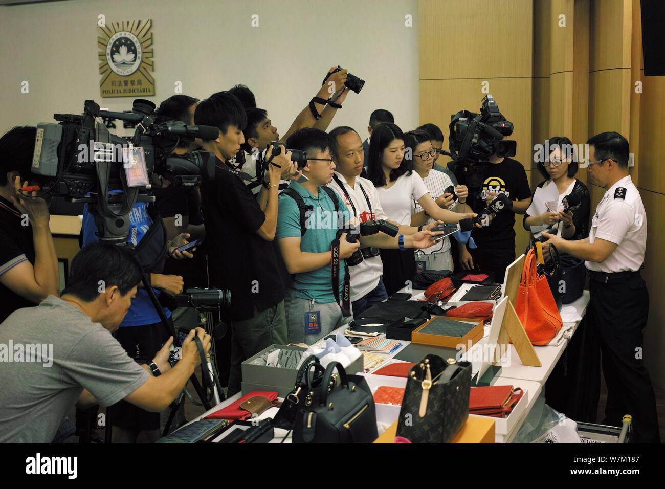 A police officer shows the fake luxury products sold by two Chinese women to customers in mainland China as he is interviewed at a police station in M Stock Photo