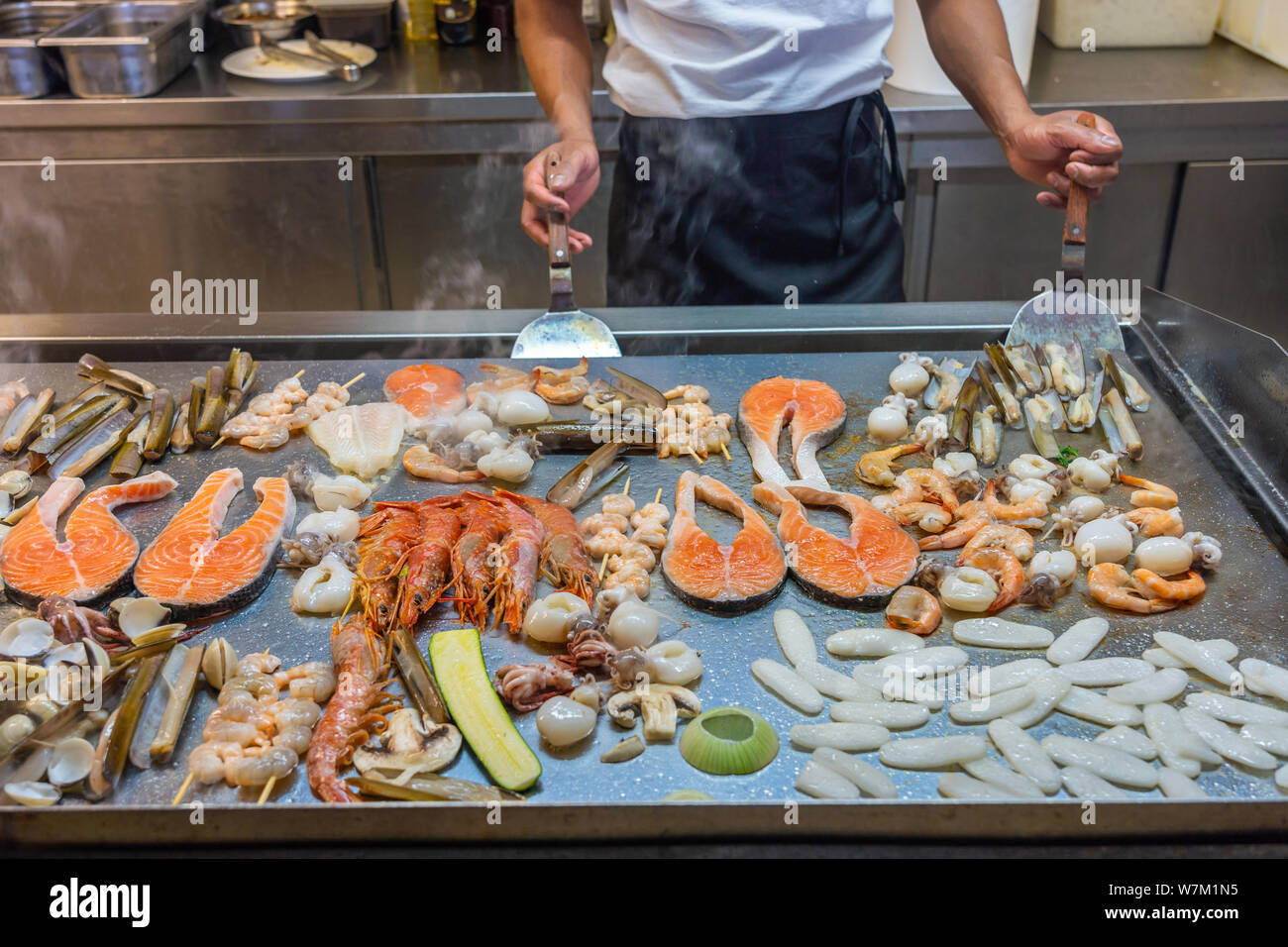 The restaurant's chef cooking seafoods on big square pan in kitchen Stock Photo