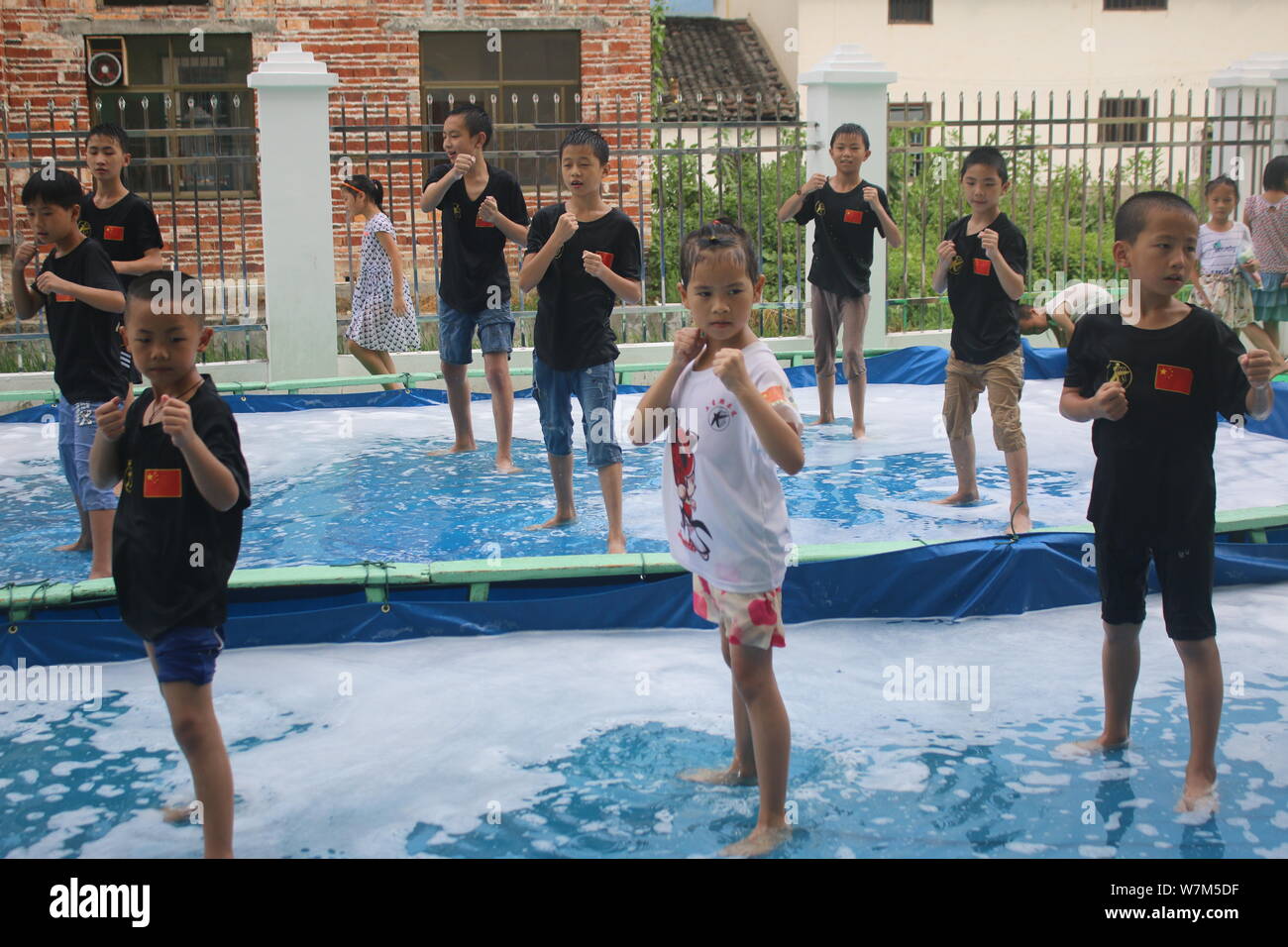 Chinese children practise martial arts in a swimming pool to cool off at a summer martial art