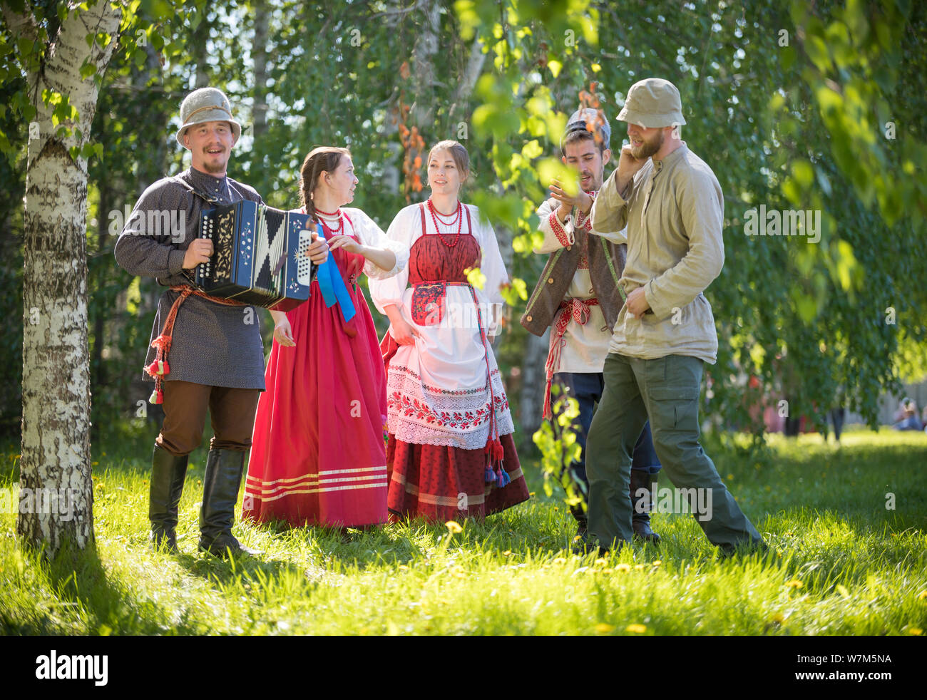 People in traditional Russian clothes are standing in the woods and ...