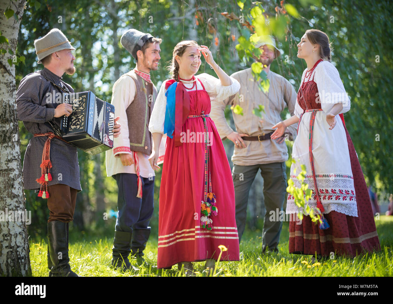 People in traditional Russian clothes communicate in the forest on the