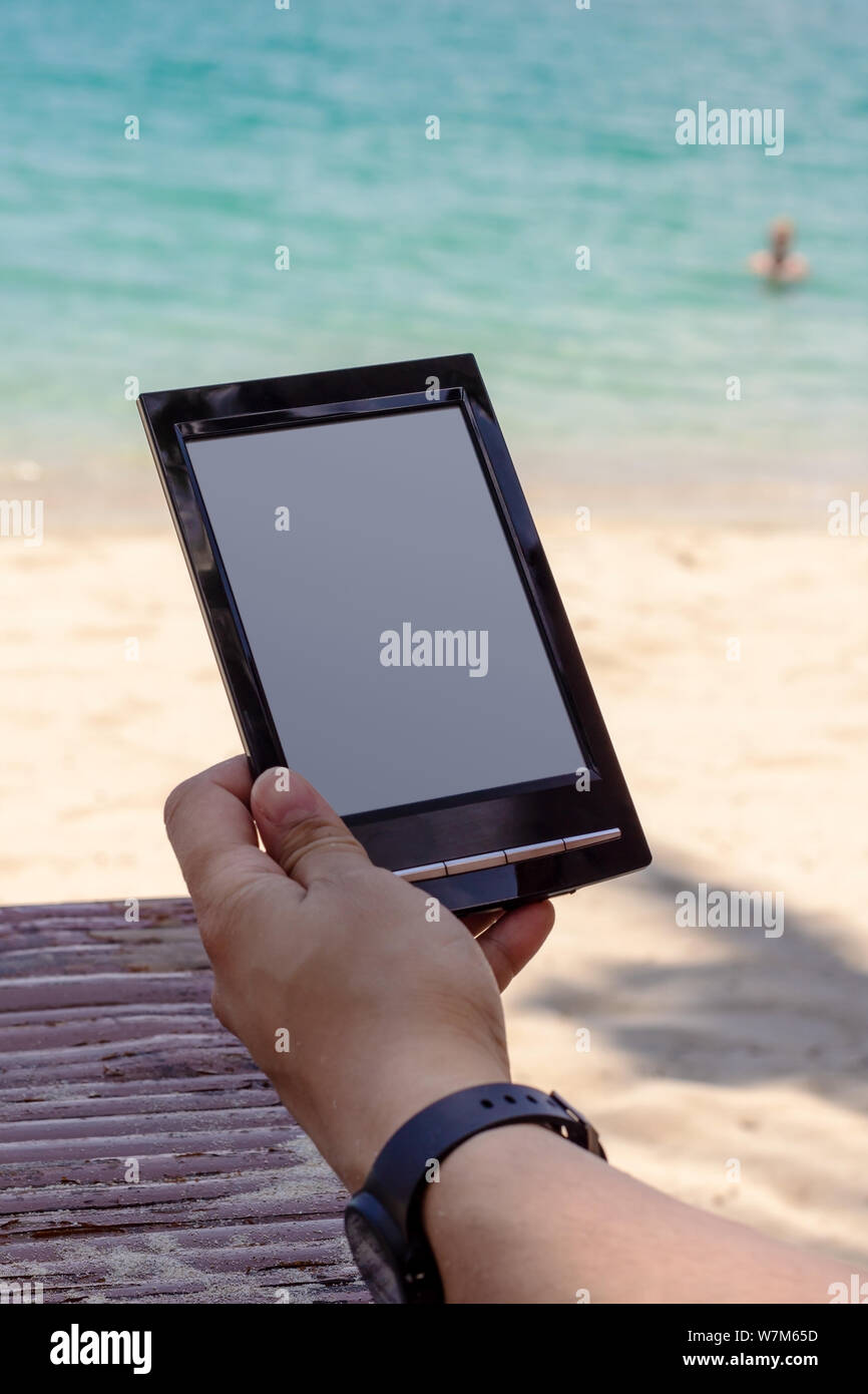 Reading on the beach with e-book reader Stock Photo