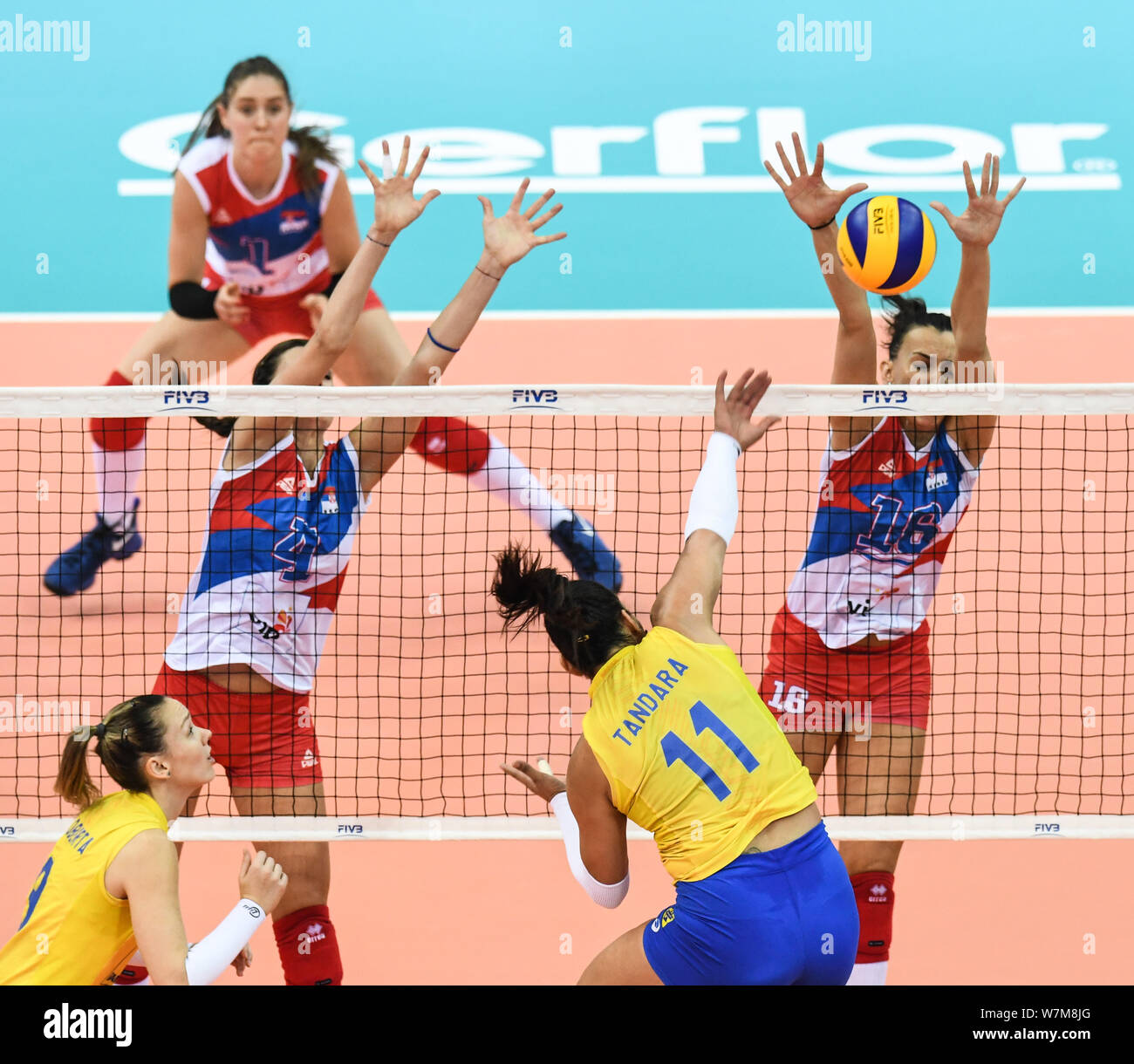 Tandara Caixeta of Brazil spikes against Bojana Zivkovic and Milena Rasic of Serbia during their match of the FIVB Volleyball World Grand Prix Finals Stock Photo