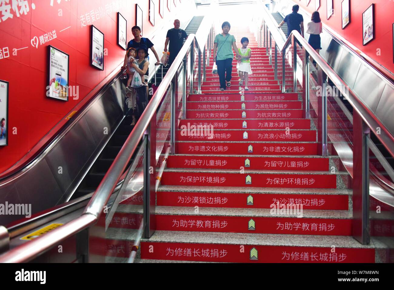 Passengers walk on stairs installed with infrared ray detectors to record steps of passengers to donate money at the Fengqi Road Station on Metro Line Stock Photo