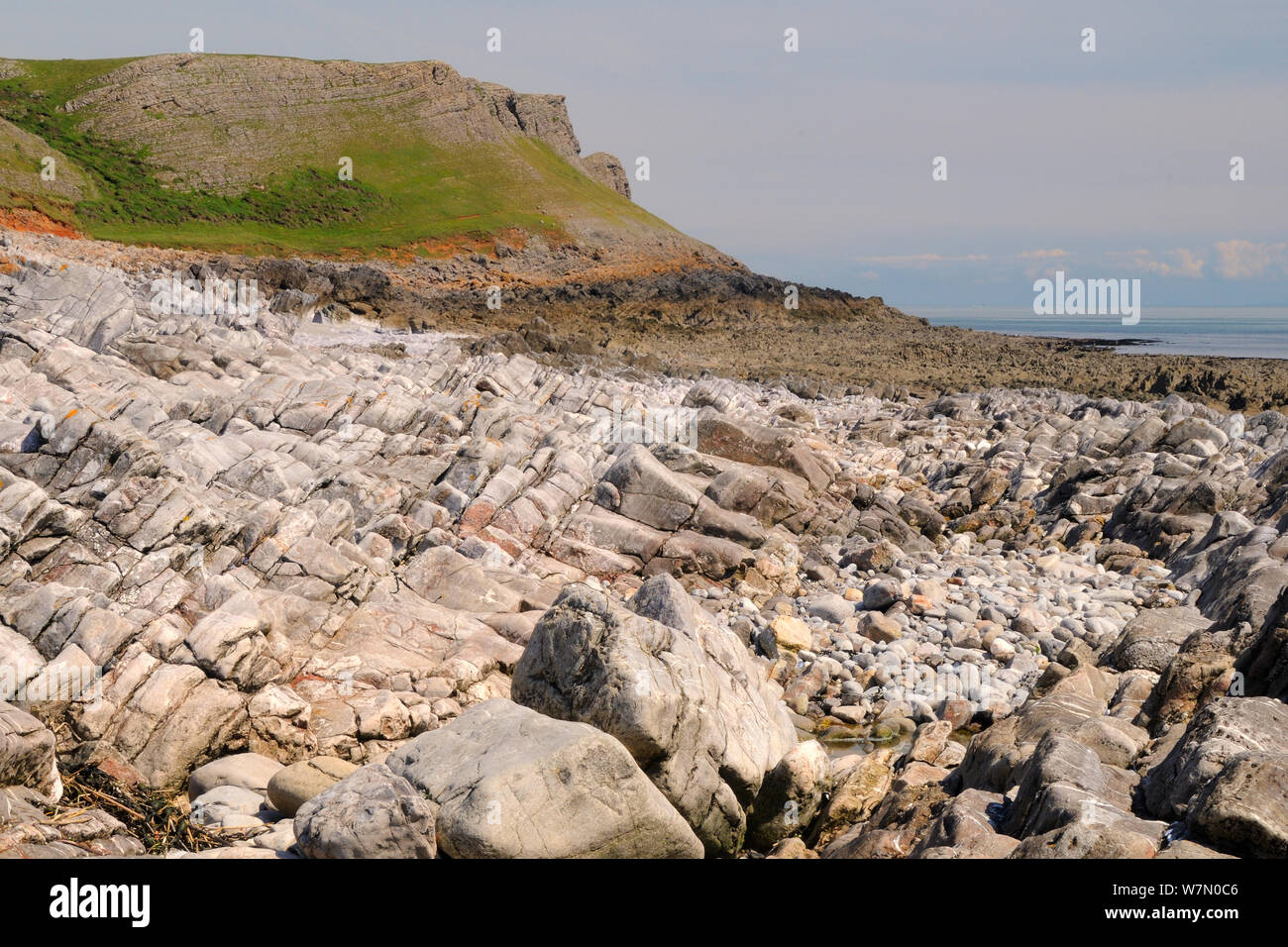 Limestone rocks, boulders and rockpool exposed at low tide with steep eroded cliffs above, near Rhossili, The Gower peninsula, Wales, UK, July. Sequence 1 of 2, matching view with different tides Stock Photo