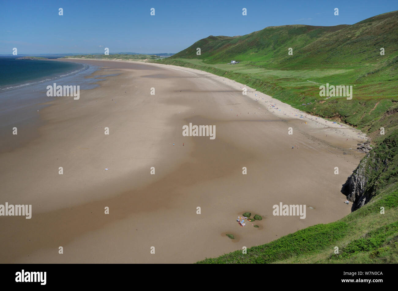 Overview of Rhossili Bay at low tide with many people relaxing on the huge sandy beach below Rhossili Down, The Gower peninsula, Wales, UK, July. Sequence 1 of 2, matching view with different tides Stock Photo