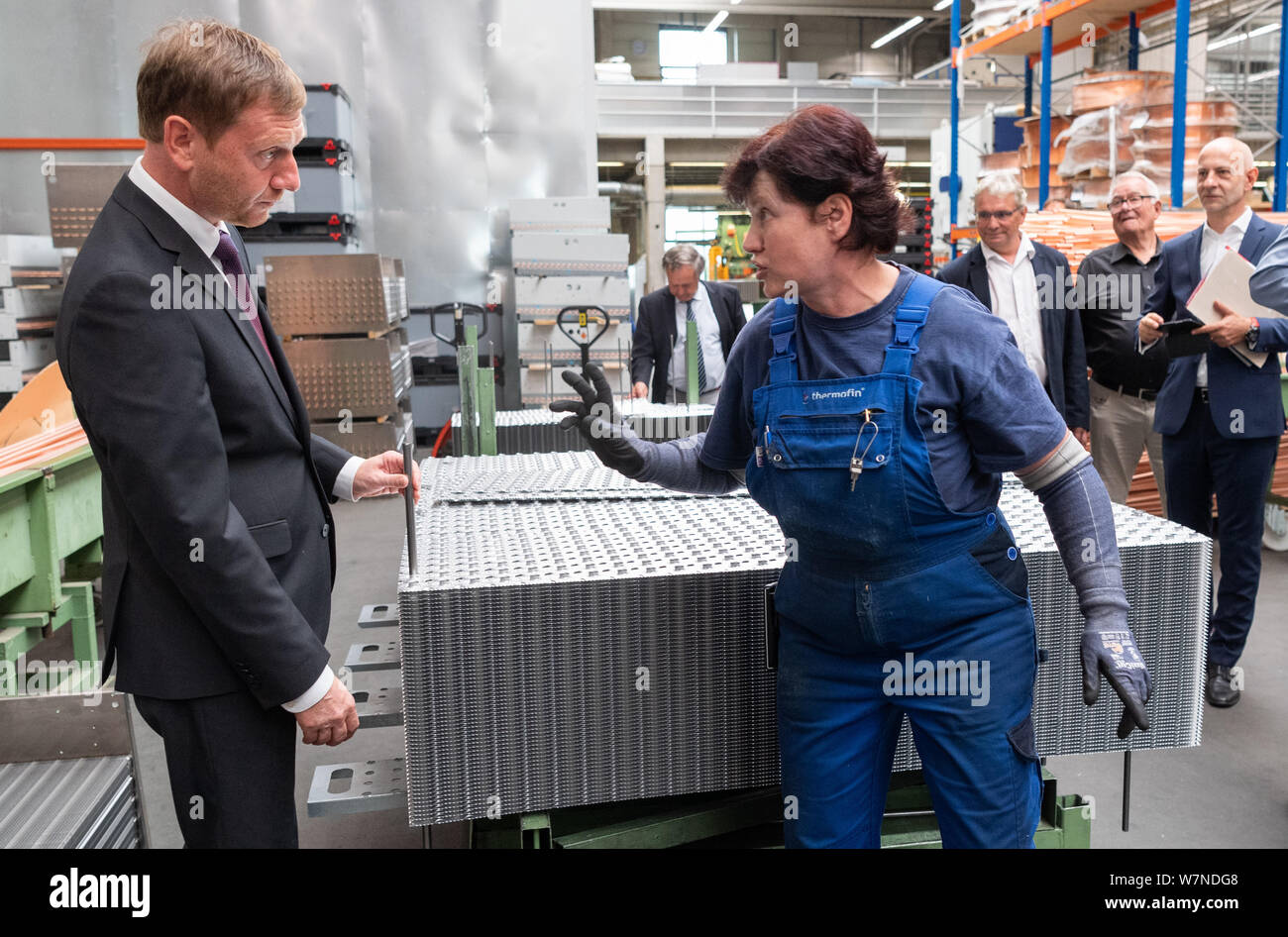 Heinsdorfergrund, Germany. 07th Aug, 2019. Michael Kretschmer (CDU, l), Prime Minister of Saxony, is explained how to assemble heat exchangers by Elke Wentsche during a tour of the Thermofin GmbH production facility. Thermofin is an internationally active company in the production of components for refrigeration and air conditioning. Credit: Robert Michael/dpa-Zentralbild/dpa/Alamy Live News Stock Photo