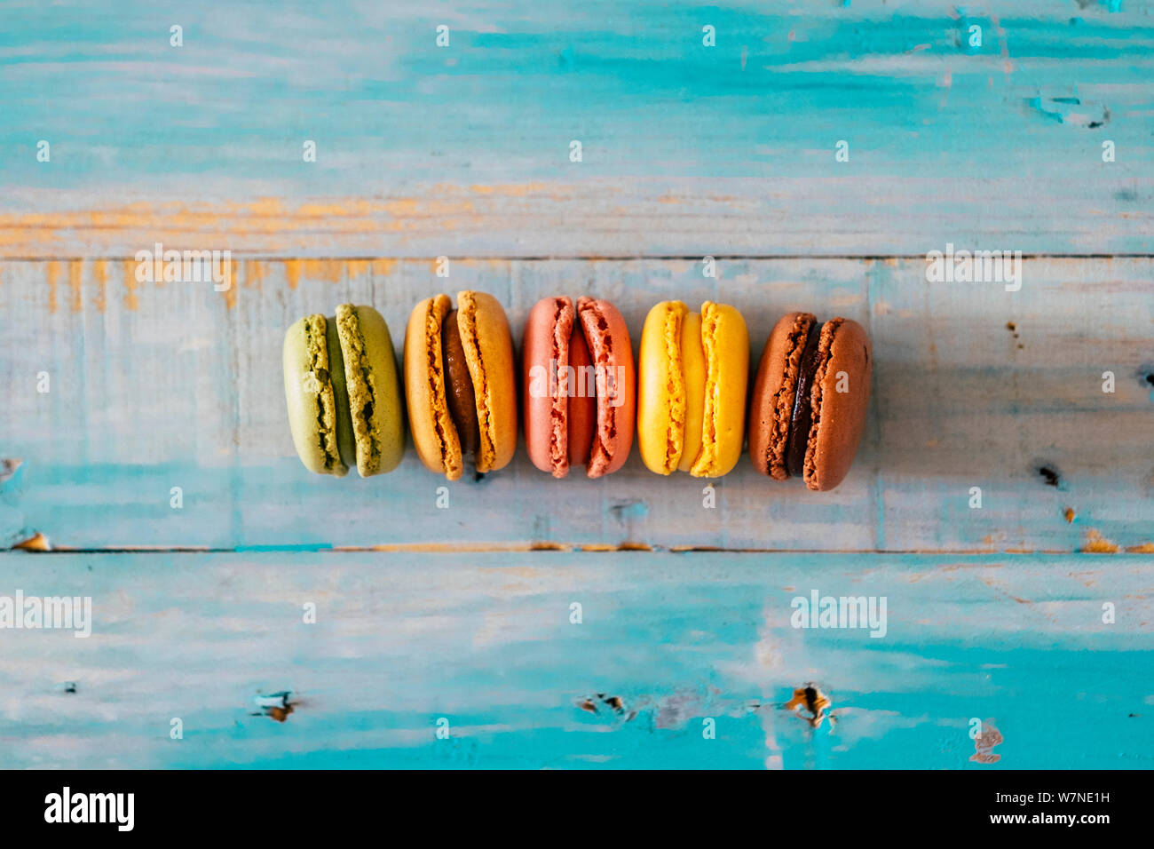 Coloured macarones biscuits on a blue wooden table background - concept of bakery and party lifestyle with sweet snacks - food decorations viewed from Stock Photo