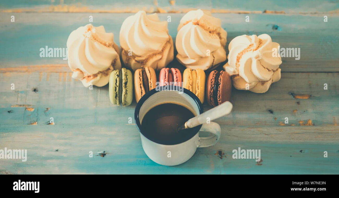 Vintage style sweet breakfast concept with coffee and macarones biscuits little cakes on a blue wooden background viewed from above - food and sweet b Stock Photo