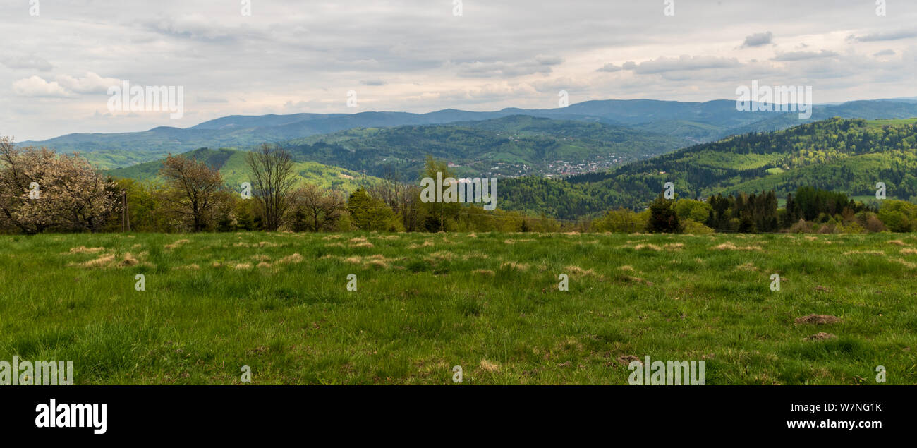 Beskid Slaski mountain range panorama from meadow bellow Wielka Czantoria hill on polish-czech borders during springtime day with mostly cloudy sky Stock Photo
