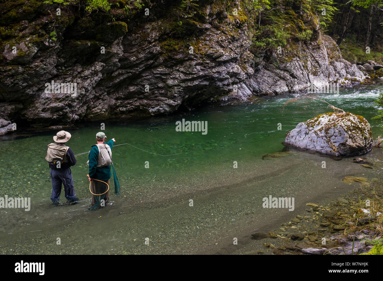 Two fly fishermen fishing to 'sighted' brown trout (Salmo trutta) in a clear 'backcountry' river, North Canterbury South Island, New Zealand. December, 2011. Stock Photo