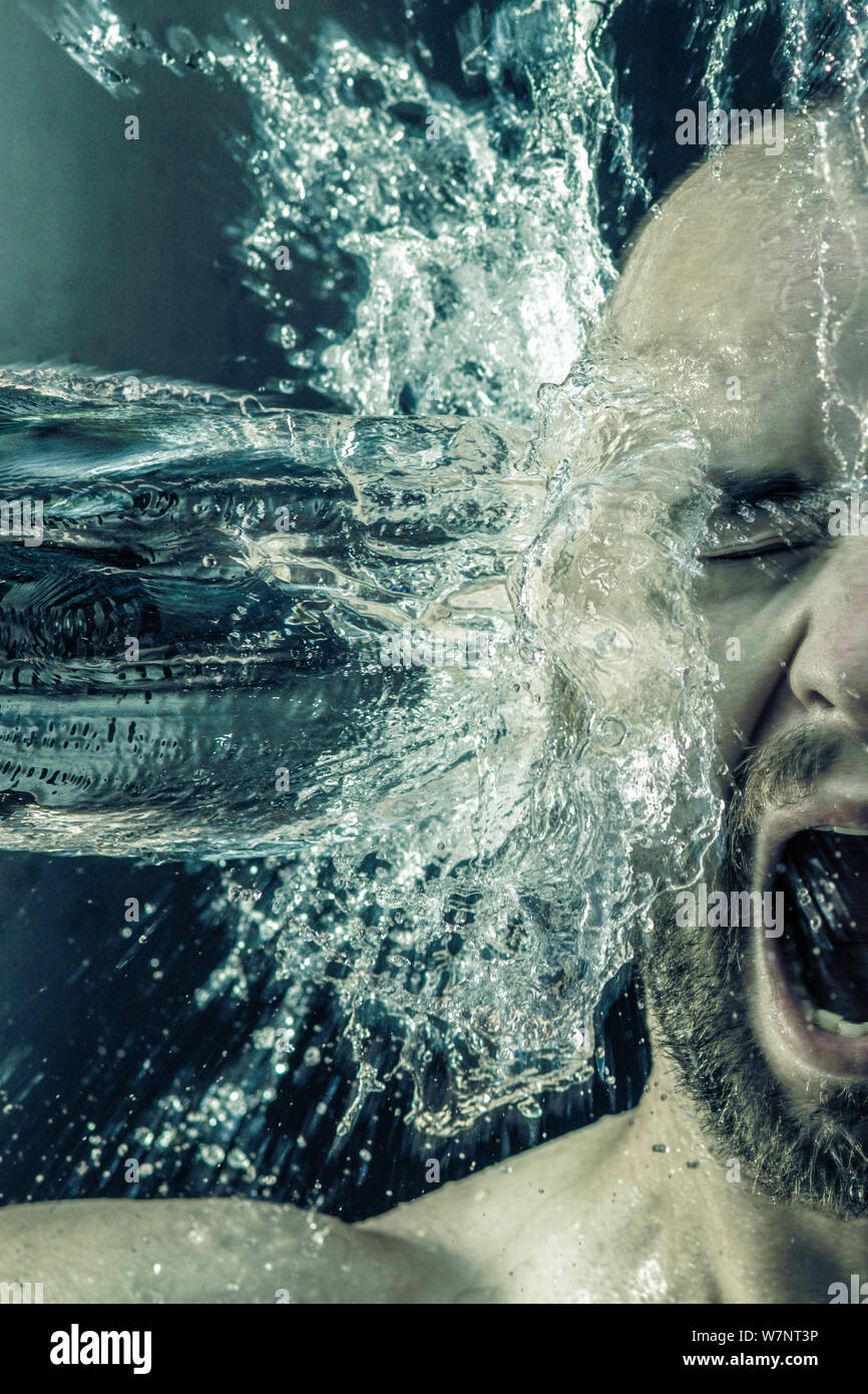 portrait of a man receiving a bucket of water in his face, high-speed photography. Stock Photo