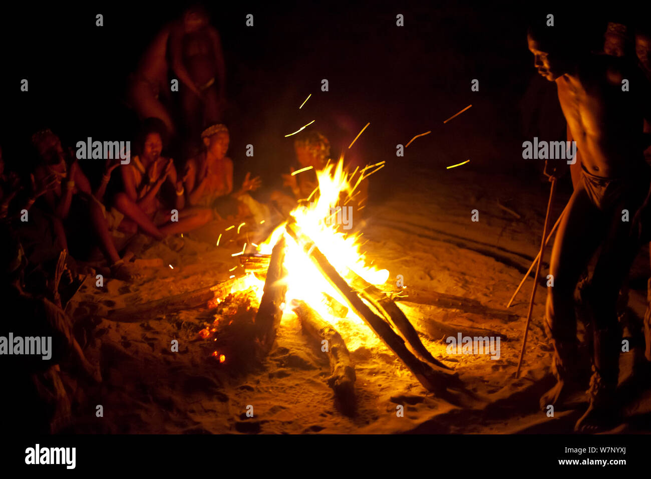 Zu/'hoasi Bushmen carry out a traditional Trance Dance. Women clap and sing by a fire while men dance in a circle in preparation for a Sangoma (Zulu healer) to perform traditional healing while in an altered state of consciousness. Kalahari, Botswana. April 2012. Stock Photo