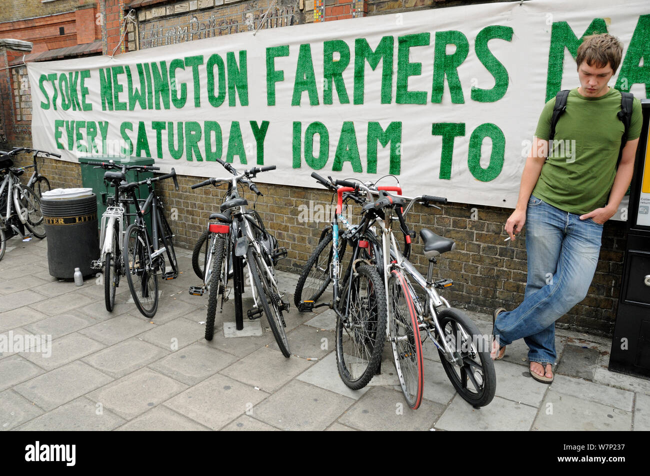 Sign outside Stoke Newington Farmers Market with parked bicycles and man, London Borough of Hackney, UK, August 2009 Stock Photo