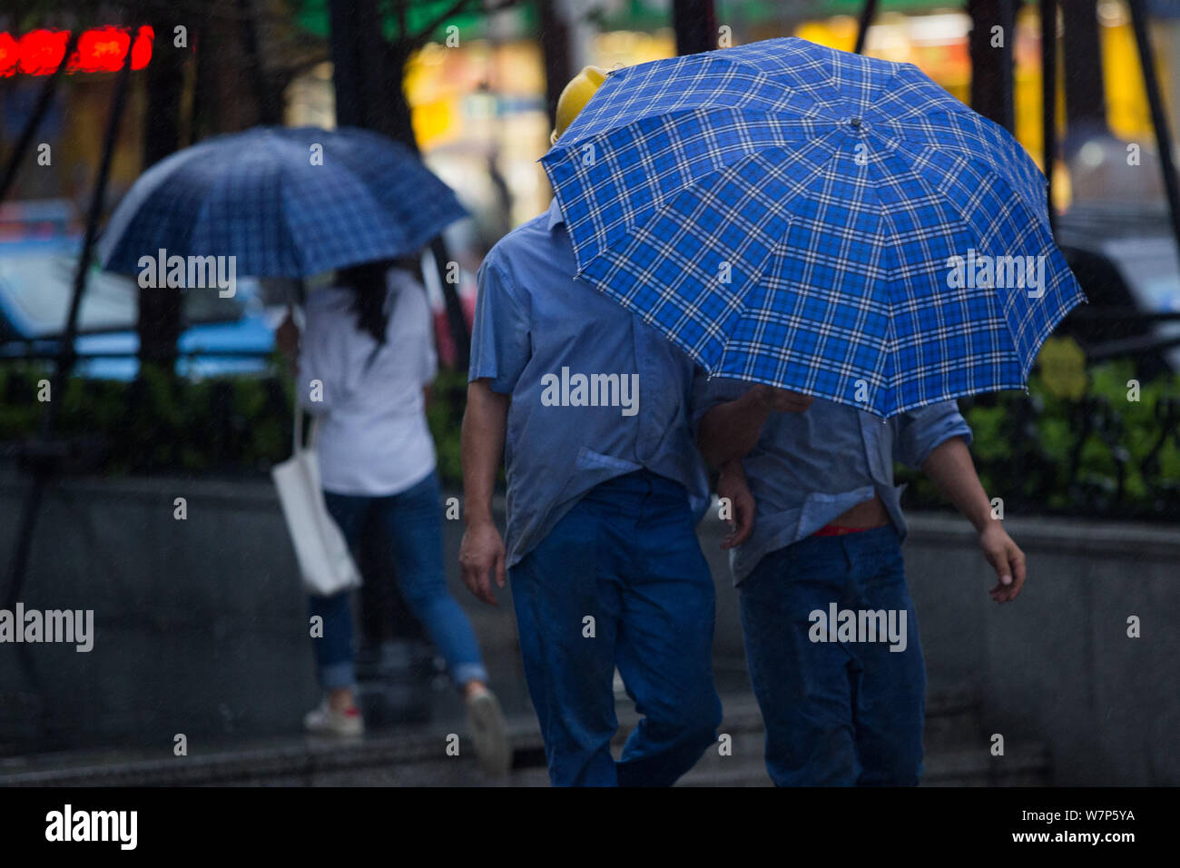 Chinese commuters struggle with their umbrellas in heavy rain and strong wind caused by Typhoon Merbok on a road in Shenzhen city, south China's Guang Stock Photo