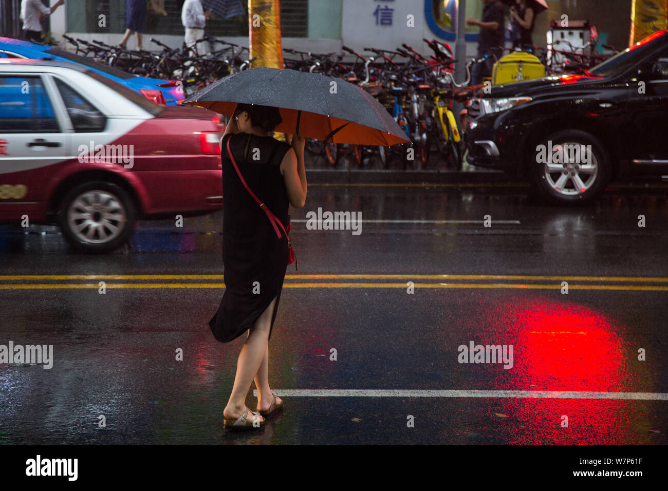 A Chinese commuter struggles with her umbrella in heavy rain and strong wind caused by Typhoon Merbok on a road in Shenzhen city, south China's Guangd Stock Photo