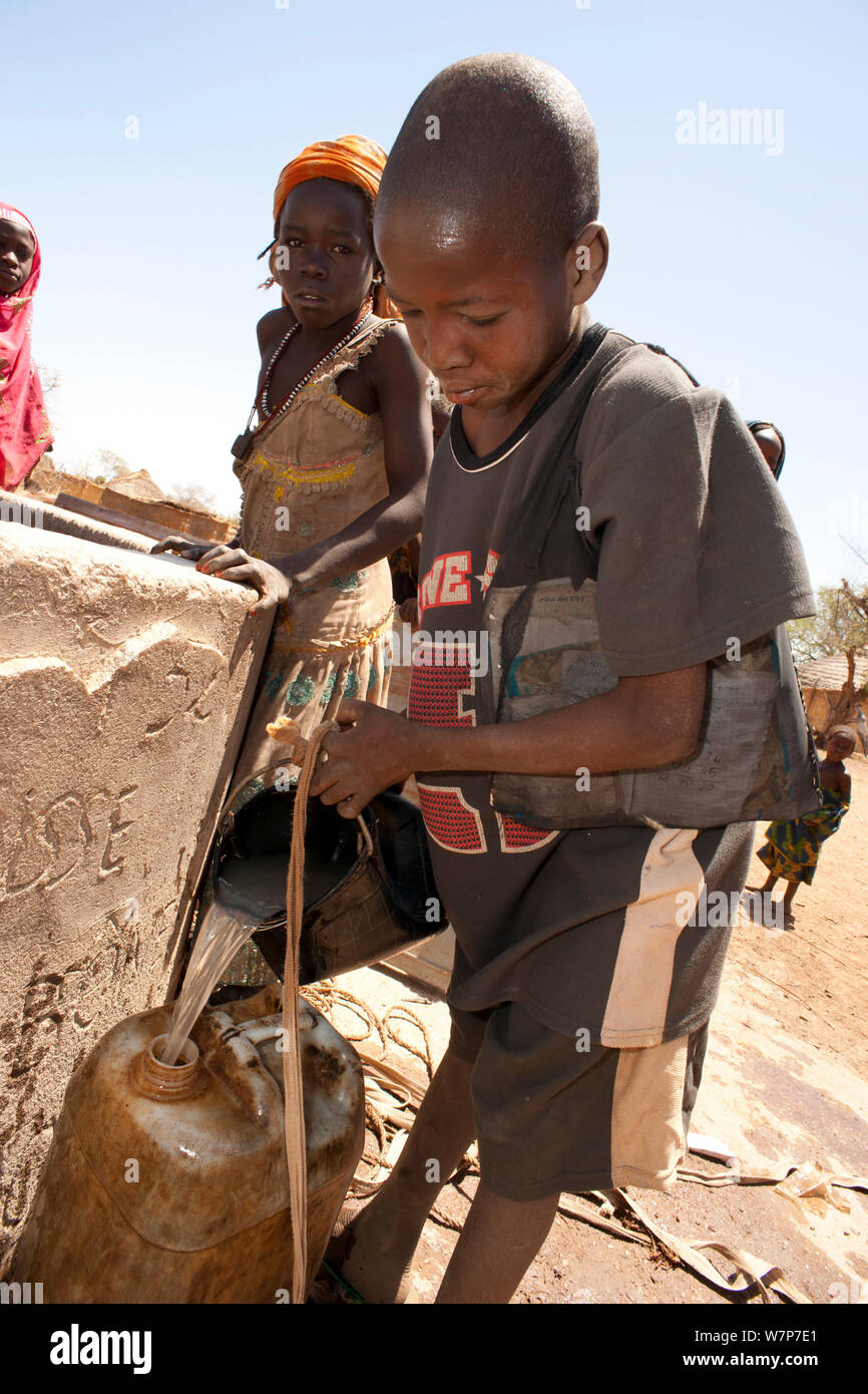 Gula boy drawing water from well; these people are Magreb Arab descendants originally from Sudan. Precious water is drawn from a communal well each day by women and children in the village of Bon near Zakouma National Park, Chad. 2010 Stock Photo