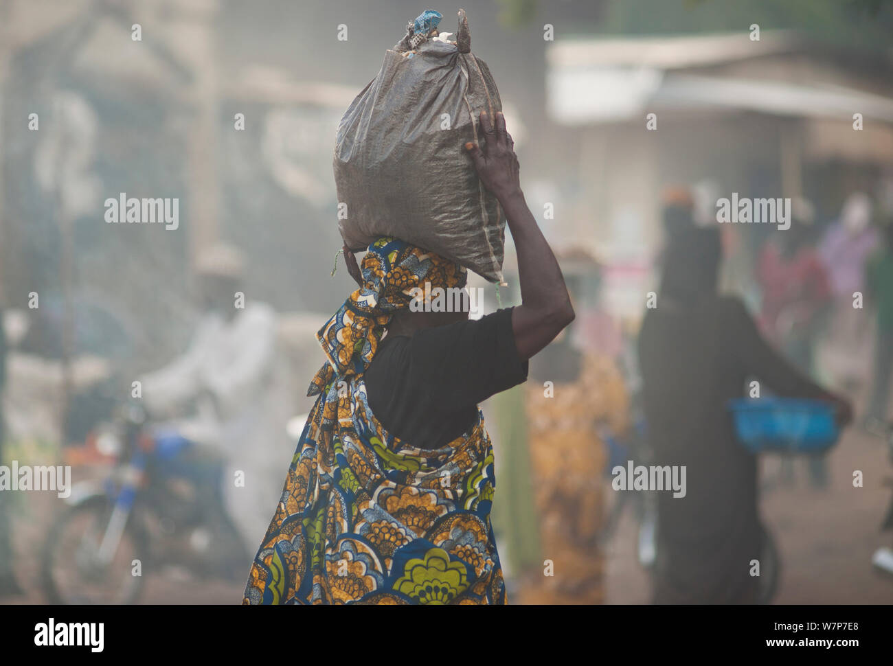 Street market with woman carrying bag of charcoal on her head. Maroua, Northern Cameroon, September 2009 Stock Photo